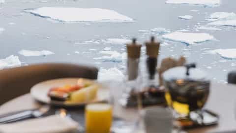 A table set for breakfast with a view of icebergs - Le Commandant Charcot, Ponant Cruises
