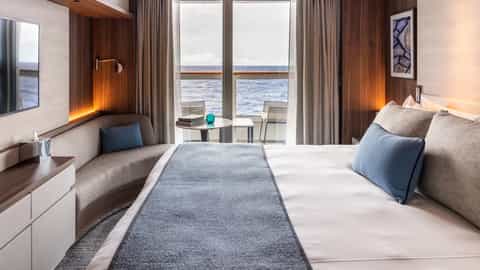 A modern cruise ship suite with a bed and balcony - Le Commandant Charcot, Ponant Cruises