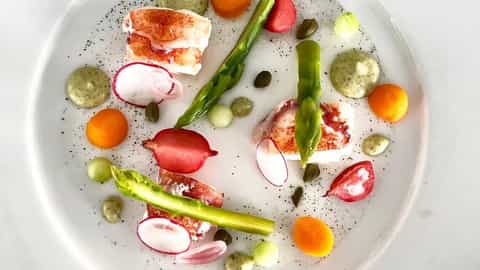A plate of lobster, asparagus, and colorful vegetables - Le Jacques Cartier, Ponant Cruises