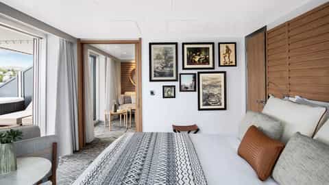 A suite bedroom with a balcony and a separate seating area - Le Laperouse, Ponant Cruises