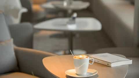 A cup of coffee sits on a table next to a book - Le Lyrial, Ponant Cruises