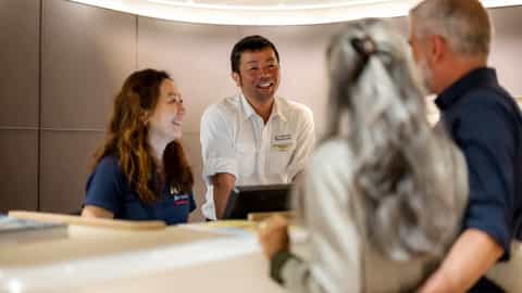 A couple interacts with ship staff at a desk - Le Ponant, Ponant Cruises