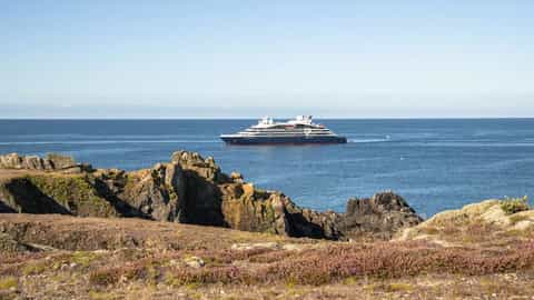 A cruise ship sails on the blue ocean near a rocky coast - Le Ponant, Ponant Cruises