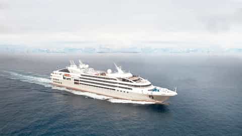 A cruise ship sails through the ocean with icebergs in the distance - Le Soleal, Ponant Cruises