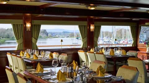 Set dining tables with a view of a marina - Lord of the Glens, Lindblad Expeditions