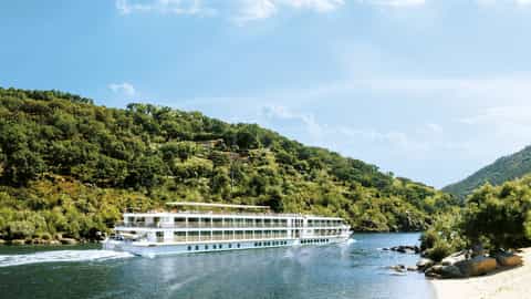 A river ship sails on a calm river by a sandy shore - ms Amalia Rodrigues, CroisiEurope