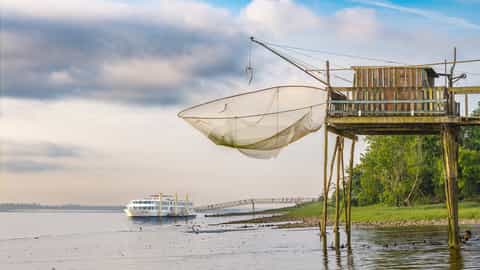 A river ship is docked near a traditional fishing station - ms Cyrano de Bergerac, CroisiEurope
