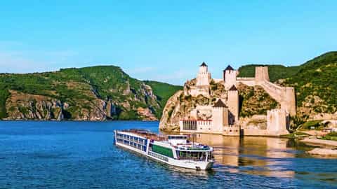 A river ship sails past a historic castle - AmaBella, AmaWaterways