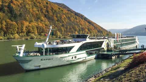 A river ship is docked by a hill with autumn trees - MS Esprit, Riviera Travel