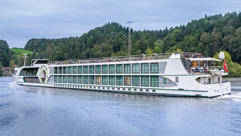 A white river ship sails on a body of water - MS Esprit, Riviera Travel