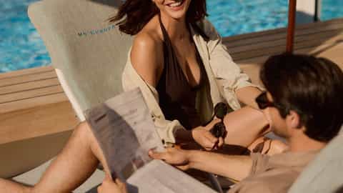 A couple relaxes on lounge chairs by the pool - ms Europa, Hapag-Lloyd Cruises