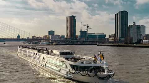 A river ship sails past a city skyline - MS Geoffrey Chaucer, Riviera Travel