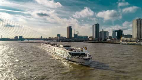 A river ship sails past a city skyline - MS Geoffrey Chaucer, Riviera Travel