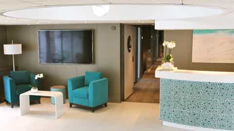A reception area with teal chairs and a desk - ms Gil Eanes, CroisiEurope