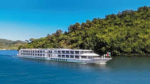 A river cruise ship sails on a blue waterway - ms Gil Eanes, CroisiEurope