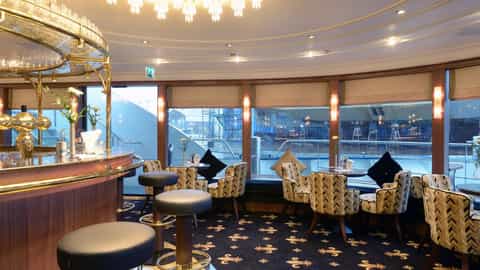 A bar lounge with seating and views of a waterway - MS Jane Austen, Riviera Travel