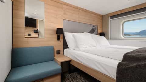 A cabin with a bed and a view of mountains and water - MS Kong Harald, Hurtigruten