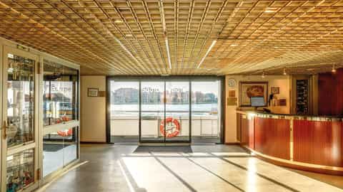 A ship's lobby with a reception desk and view of the water - ms L'Europe, CroisiEurope