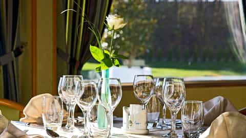 A table is set with glasses, cutlery and a rose - ms L'Europe, CroisiEurope