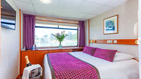 A cabin with a bed, window view, and champagne - ms La Belle de Cadix, CroisiEurope