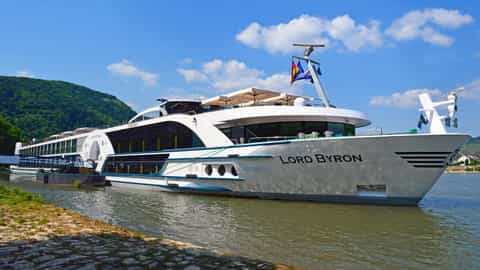 A white river cruise ship is docked on a sunny day - MS Lord Byron, Riviera Travel