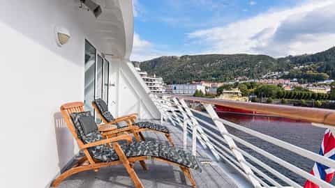 Two lounge chairs on a ship's balcony overlooking a town - MS Midnatsol, Hurtigruten