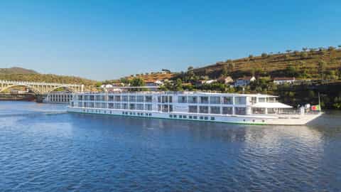 A river cruise ship sails on a blue river - MS Miguel Torga, CroisiEurope