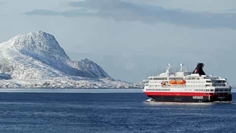 A ship sails past snowy mountains on the water - MS Nordkapp, Hurtigruten
