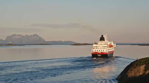 A ship sails on calm water near islands and mountains - MS Nordlys, Hurtigruten
