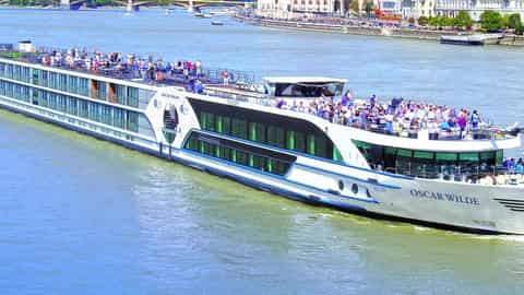 A large river cruise ship sails past a European city - MS Oscar Wilde, Riviera Travel