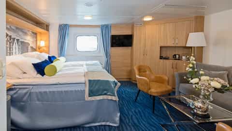 A ship suite with a bed, seating area, and storage - MS Polarlys, Hurtigruten