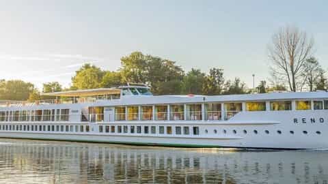 A white river ship sails on a calm waterway - ms Renoir, CroisiEurope