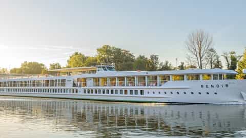 A white river ship sails on a calm waterway - ms Renoir, CroisiEurope