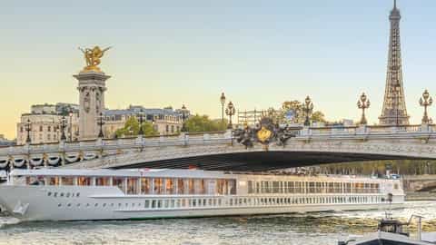 A river ship passes under a bridge in Paris - ms Renoir, CroisiEurope