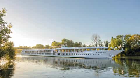 A white river ship sails on a calm waterway - ms Renoir, CroisiEurope