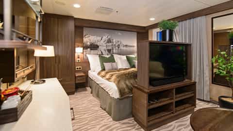 A well-appointed suite bedroom with a large bed and seating area - MS Richard With, Hurtigruten