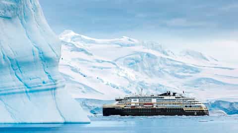 A ship sails past a large iceberg in Antarctica - MS Roald Amundsen, HX Expeditions