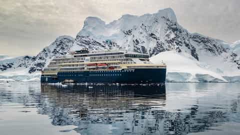 A ship sails in front of snow-covered mountains - MS Roald Amundsen, HX Expeditions