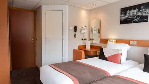 A cabin with two beds, a desk, and a mirror - ms Seine Princess, CroisiEurope