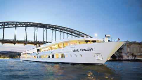 A white riverboat sails under a bridge - ms Seine Princess, CroisiEurope