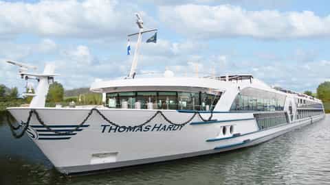 A white riverboat sails on calm water under a cloudy sky - MS Thomas Hardy, Riviera Travel