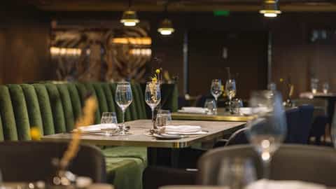 A dimly lit dining room with tables set for dinner - MS Trollfjord, Hurtigruten