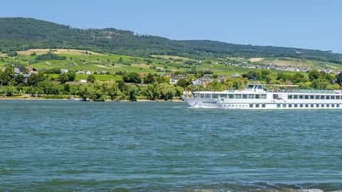 A river ship sails past a scenic landscape - ms Victor Hugo, CroisiEurope