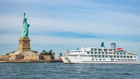 A cruise ship sails past the Statue of Liberty - ACL American Glory, American Cruise Lines