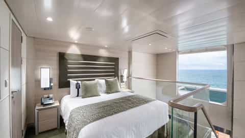 A modern suite bedroom with a large bed and ocean view - MSC Grandiosa, MSC Cruises