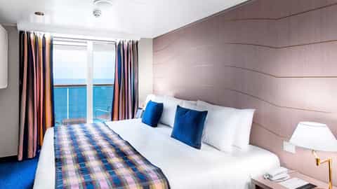 A cruise ship suite bedroom with a large bed and balcony view - MSC Lirica, MSC Cruises