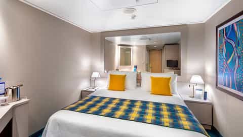 A cruise ship cabin with a bed and sitting area - MSC Lirica, MSC Cruises
