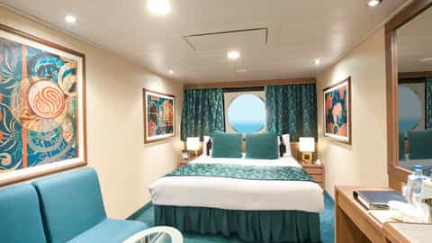 A stateroom with a bed, seating area, and porthole view - MSC Magnifica, MSC Cruises