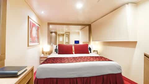 A cabin with a bed, desk, and artwork - MSC Musica, MSC Cruises