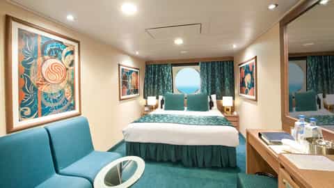 A stateroom with a bed, seating area, and porthole view - MSC Musica, MSC Cruises